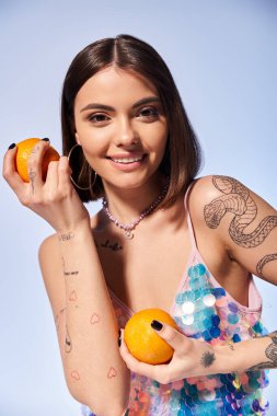 Bir elinde portakal, diğer elinde meyve dilimi olan esmer saçlı genç bir kadın..