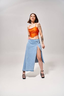 A brunette woman in a stylish skirt and top strikes a confident pose in a studio setting. clipart