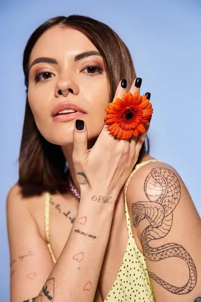 stock image A brunette woman holds a delicate flower in her hand, exuding grace and elegance in a studio setting.