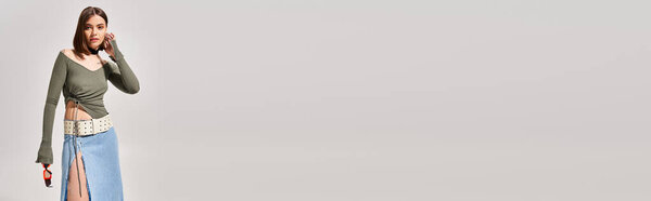 Стильная молодая женщина с брюнетками в джинсовой юбке, в студии.