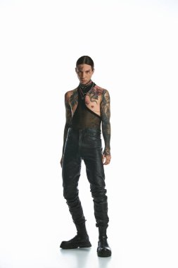 A young man with tattoos confidently stands in front of a white background. clipart