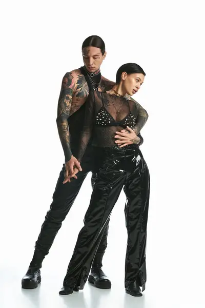 stock image A young tattooed couple waltzing gracefully in a studio against a grey background.