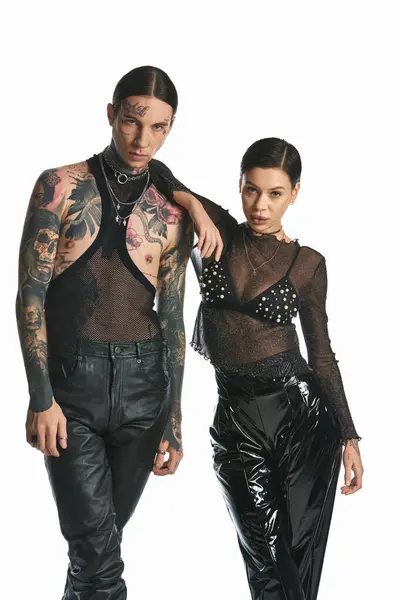 一个年轻的 时髦的男人和一个有纹身的女人站在一个灰色背景的工作室里 — 图库照片