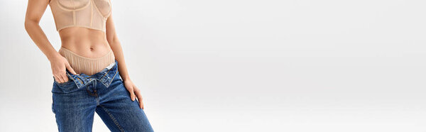 Молодая женщина занимает стильную позу в джинсах и майке.