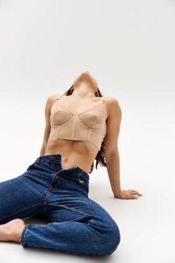 Yerde yatan bir kadın, kot pantolona güven ve tarz yayıyor..