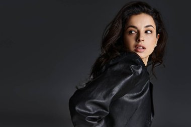 Siyah ceketli şık bir kadın kameraya poz veriyor..