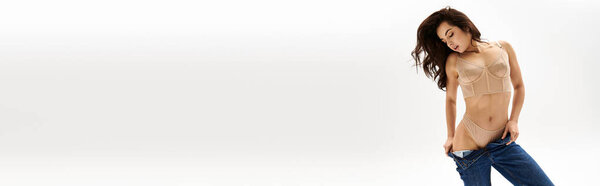Молодая женщина, ставящая горячую позу в лифчике и джинсах.