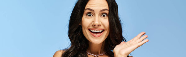 A stylish woman in sunglasses with a face expression, holding her hands out in a studio setting on a blue background.