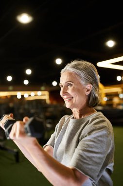 Spor kıyafetleri içinde güzel bir kadın spor salonunda halterlerle aktif egzersiz yapıyor.