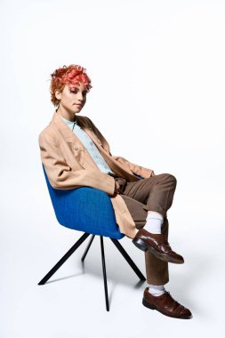 Alevli kızıl saçlı olağanüstü bir kadın parlak mavi bir sandalyede dinleniyor..
