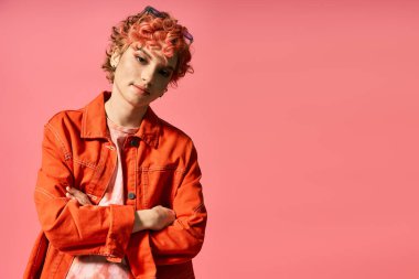 Pembe arka planda duran kızıl saçlı genç bir kadın..