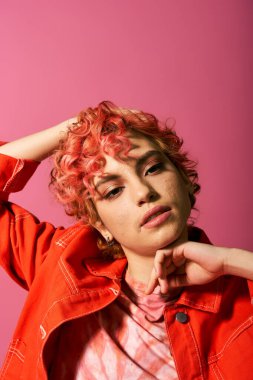 Pembe saçlı ve çarpıcı kırmızı ceketli bir kadın göze çarpıyor..