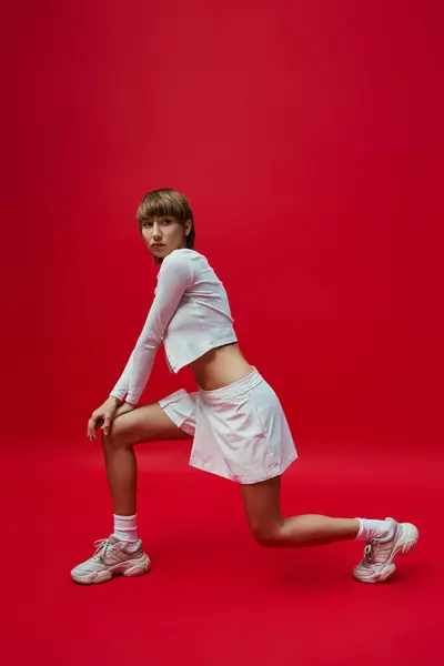 Young Woman White Dress Tennis Shoes Stands Confidently Vibrant Red — Stockfoto