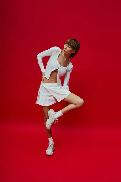 Young Woman White Dress Striking Pose Vibrant Red Backdrop — Foto Stock