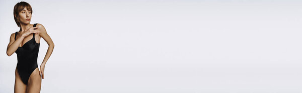 A stylish young woman in a black swimsuit striking a pose.