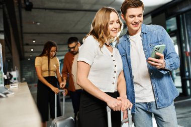 A man and woman, stand next to each other in an airport during a corporate trip. clipart