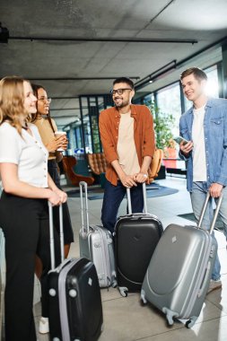 Multicultural colleagues in casual attire gathered in a hotel lobby with luggage, preparing for a corporate trip. clipart