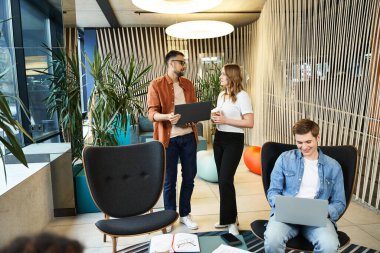 Bir grup meslektaş, birlikte çalıştığı bir yerde dizüstü bilgisayarlarıyla ayakta durarak modern bir iş hayatı sürdürüyorlar..