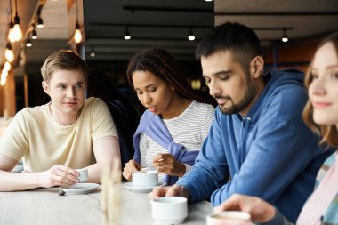 A diverse group of colleagues from a startup team enjoy a meal together, fostering teamwork and bonding in a modern business setting. clipart