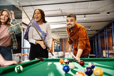 Ortak çalışma alanındaki meslektaşlar bilardo oynuyorlar, modern bir iş ortamında takım çalışmasını ve arkadaşlığı teşvik ediyorlar..