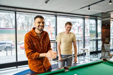 Two men strategizing and playing pool in a coworking space, reflecting a modern business lifestyle with a startup team vibe. clipart