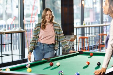 İki kadın, çalışma alanındaki meslektaşlar, dostça bir bilardo oyunu oynuyorlar, takım çalışması ve modern iş hayatı..