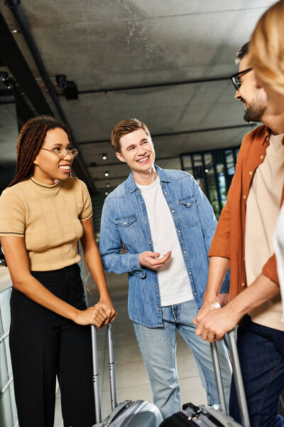 Multicultural colleagues in casual attire stand in hotel lobby with luggage, ready for corporate trip.
