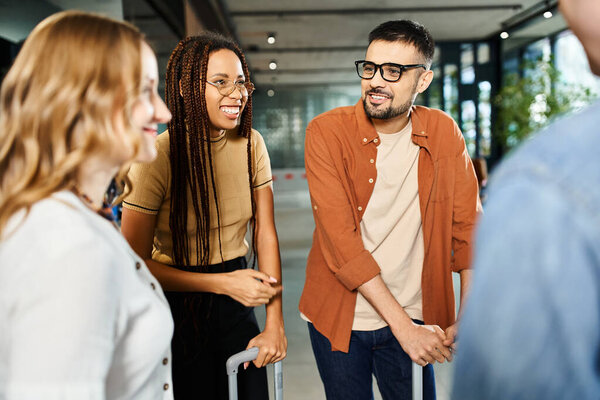 Multicultural colleagues in casual attire standing in a circle, engrossed in conversation in a hotel lobby during a corporate trip.