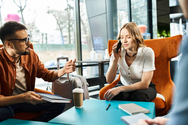 Женщина, которая разговаривает по мобильному телефону, сидя рядом с мужчиной в отеле в корпоративной поездке.