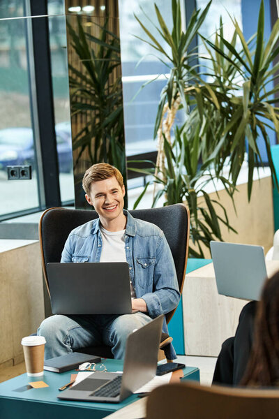 Человек, погруженный в работу, многозадачный, сидя в кресле, воплощающий современный деловой образ жизни команды стартапов.