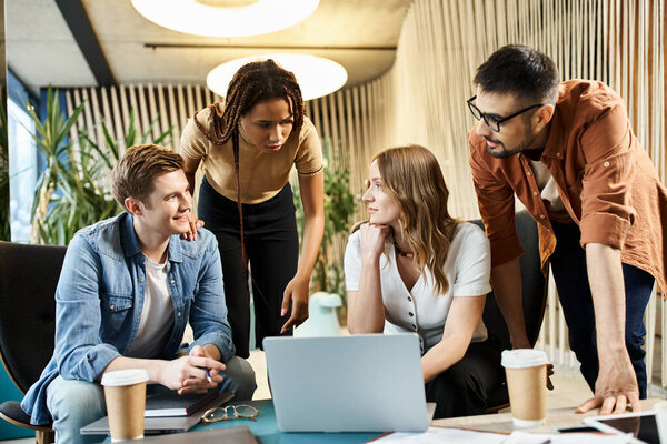 Разнообразная группа коллег из команды стартапов, участвующих в обсуждении и совместной работе вокруг ноутбука в современной деловой обстановке.