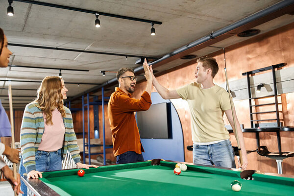 A group of colleagues from a coworking space gather around a pool table, enjoying a break and building team camaraderie.