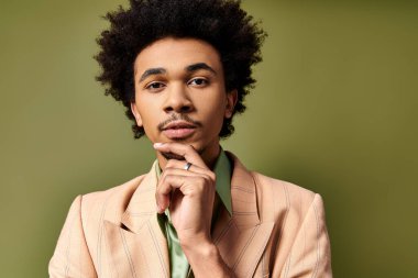 Kıvırcık, Afro-Amerikan bir adam poz veriyor, şık kıyafetler giyiyor, gururla parmağındaki yüzüğü gösteriyor..