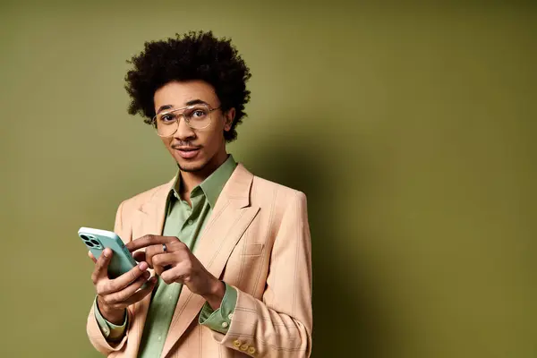 スーツとサングラスを着たスタイリッシュな若いアフリカ系アメリカ人男性は 緑色の背景に携帯電話に吸収されます — ストック写真