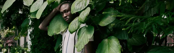 stock image Handsome African American man in dapper style surrounded by lush greenery.