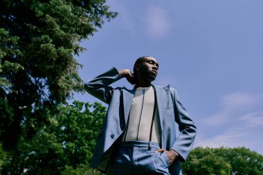 A sophisticated African American man in a suit and tie stands elegantly among vibrant green trees. clipart