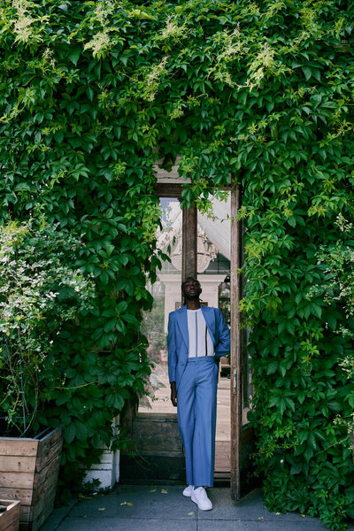A sophisticated African American man in a blue suit confidently strides into a doorway.