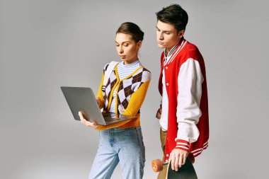 Young male and female students skateboarding while holding a laptop. clipart