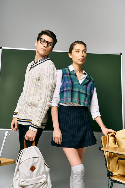 Elegant man and woman pose in front of a green board at college.