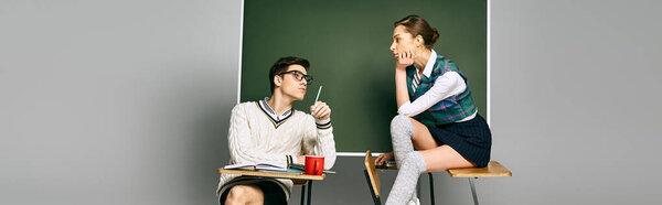Elegant male and female students sitting in front of a green chalkboard in college.