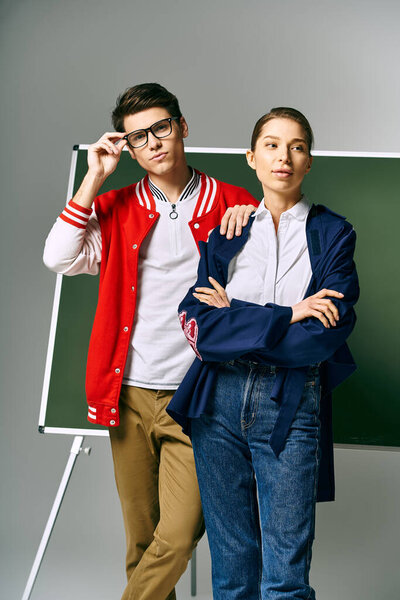 A male and female students stand in front of a green board in a college classroom.