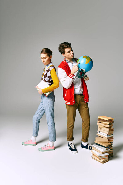 College students in casual attire stand by stacks of books in a classroom setting.