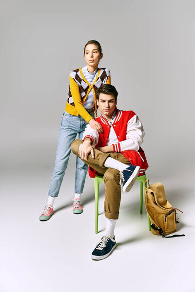 Stylish male and female students striking a pose on a chair in a college classroom.
