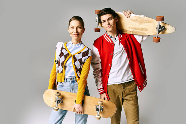 A young students showcasing skateboards in front of a gray backdrop.