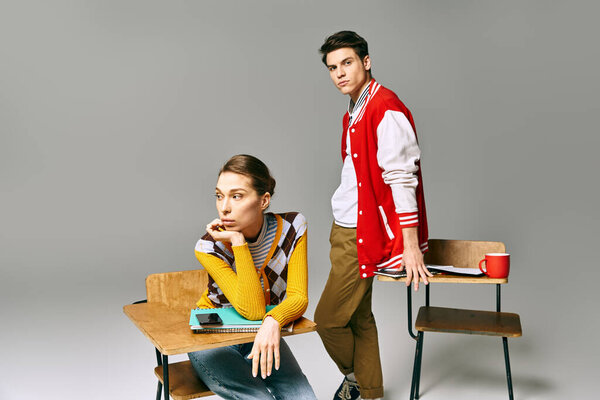 A male and female students in casual attire sit closely together on a desk in a college classroom.