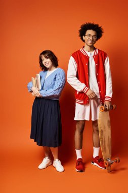 Kaykay ve kitap tutan çok kültürlü arkadaşlar bir stüdyo ortamında şık bir şekilde yan yana duruyorlar..