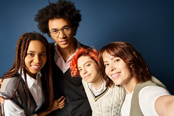 Young multicultural friends, including a nonbinary person, stand together in stylish attire, posing for a picture on a dark blue background.