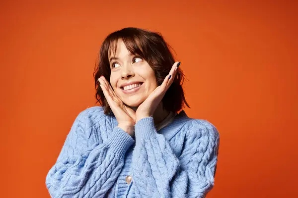 Stock image A stylish woman in a blue sweater stands, exuding a sense of happiness.