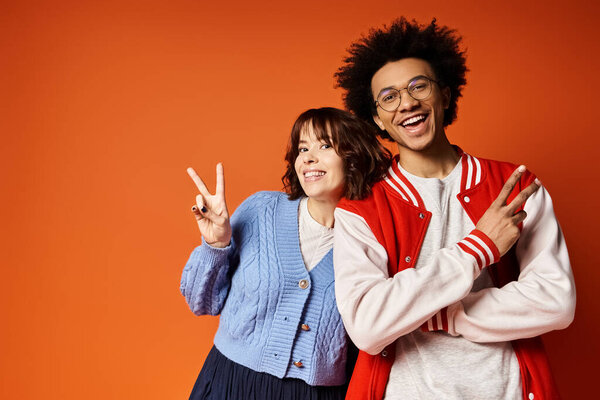 A young multicultural duo striking a pose in stylish attire in a studio setting.