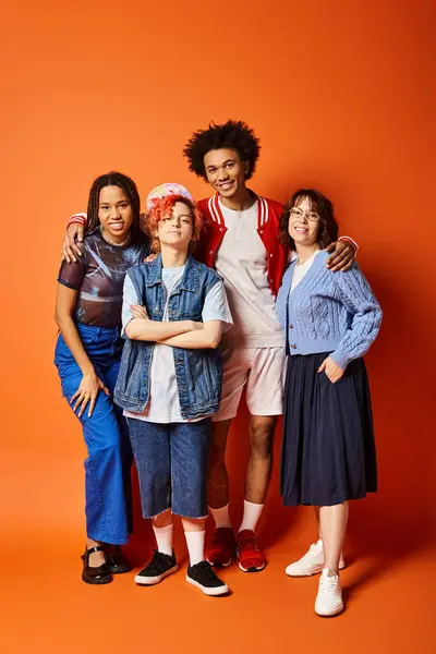 A group of young interracial friends, including a nonbinary person, standing together in stylish attire in a studio setting.